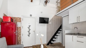 A compact kitchen with white cabinets, a red refrigerator, a wooden dining table, and a grey sofa. - Madrid Villaverde VI - Apartament with patio, AC (Madrid)