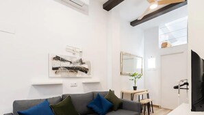 Uma sala de estar moderna com um sofá cinzento, uma mesinha e uma televisão.