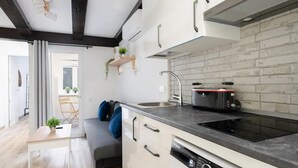 Una cocina compacta con lavavajillas integrado, microondas y fregadero.