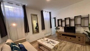 Una sala de estar con sofá, mesa de centro, televisor y espejo.