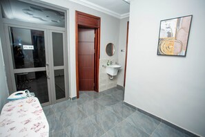 Ein Hotelzimmer mit Holztür, Badezimmer mit Waschbecken, Spiegel und Wandbild.