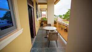 A narrow balcony with a table and chairs, a view of the street, and a large vase on the floor. - Gateway Lodge (Tamale)