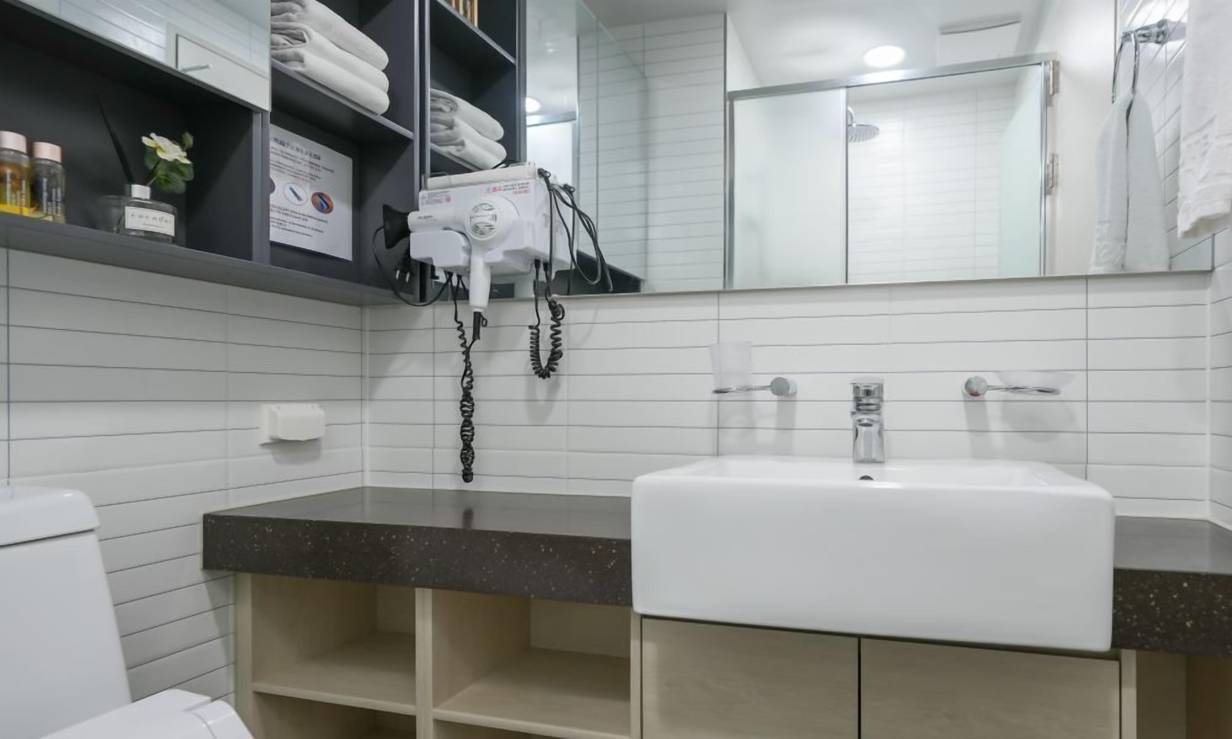 A bathroom with a white sink, a mirror, and a towel rack.