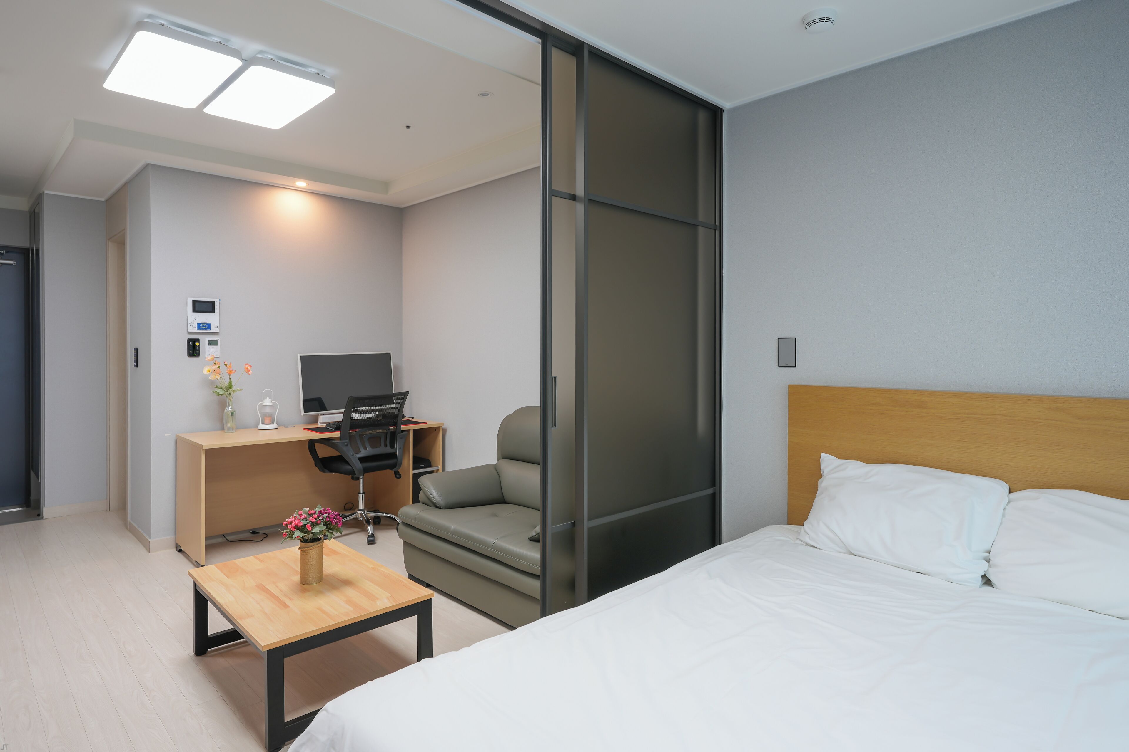 Una habitación de hotel con una cama, un escritorio, una silla, un televisor y una puerta corrediza.