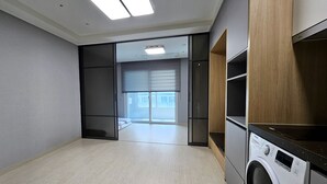 A laundry room with a washing machine, a dryer, and a sliding door leading to a balcony. - FIRSTCITY HOTEL YEOSU (Yeosu)