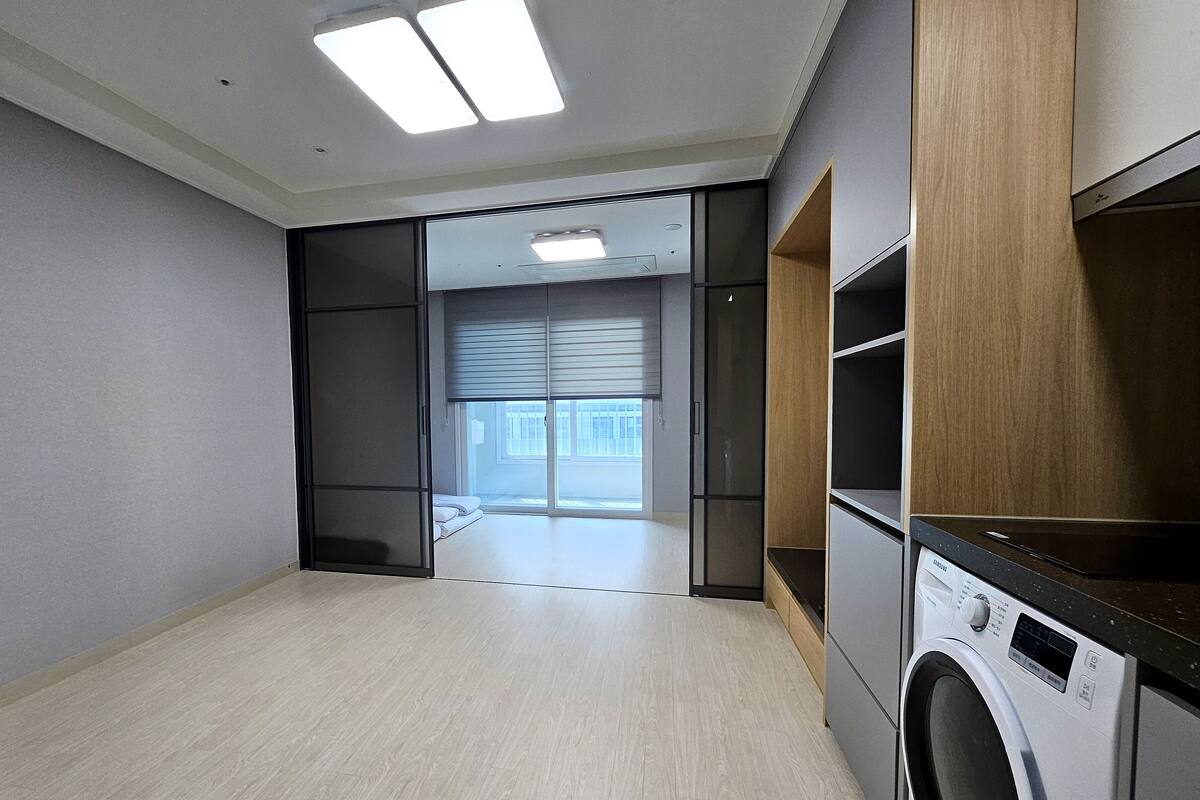 A laundry room with a washing machine, a dryer, and a sliding door leading to a balcony.