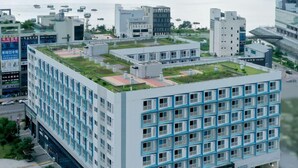 A modern building with a rooftop garden and multiple floors. - FIRSTCITY HOTEL YEOSU (Yeosu)