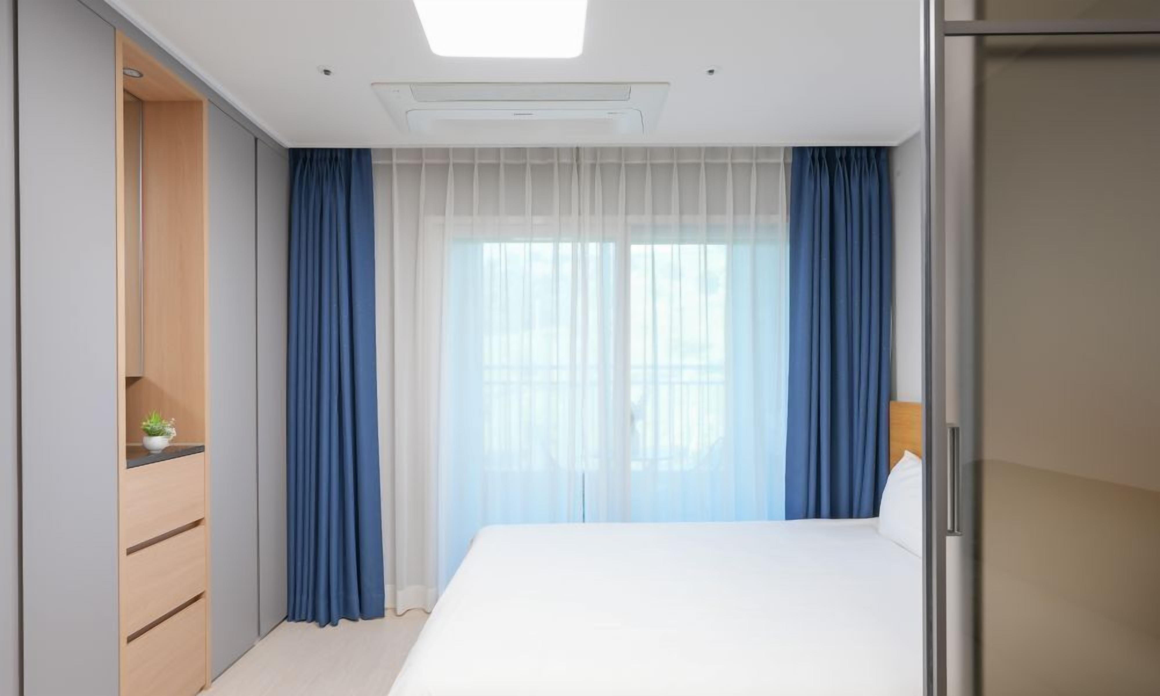 Una habitación de hotel moderna con cama, escritorio y armario.