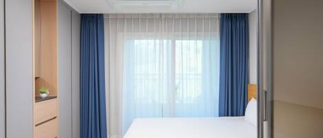 Una habitación de hotel moderna con cama, escritorio y armario.