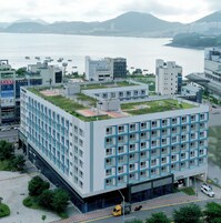 Un edificio moderno con techo plano, varios pisos y fachadas de vidrio y hormigón.