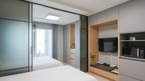 A hotel room with a bed, a TV, a microwave, and a small desk area. - FIRSTCITY HOTEL YEOSU (Yeosu)