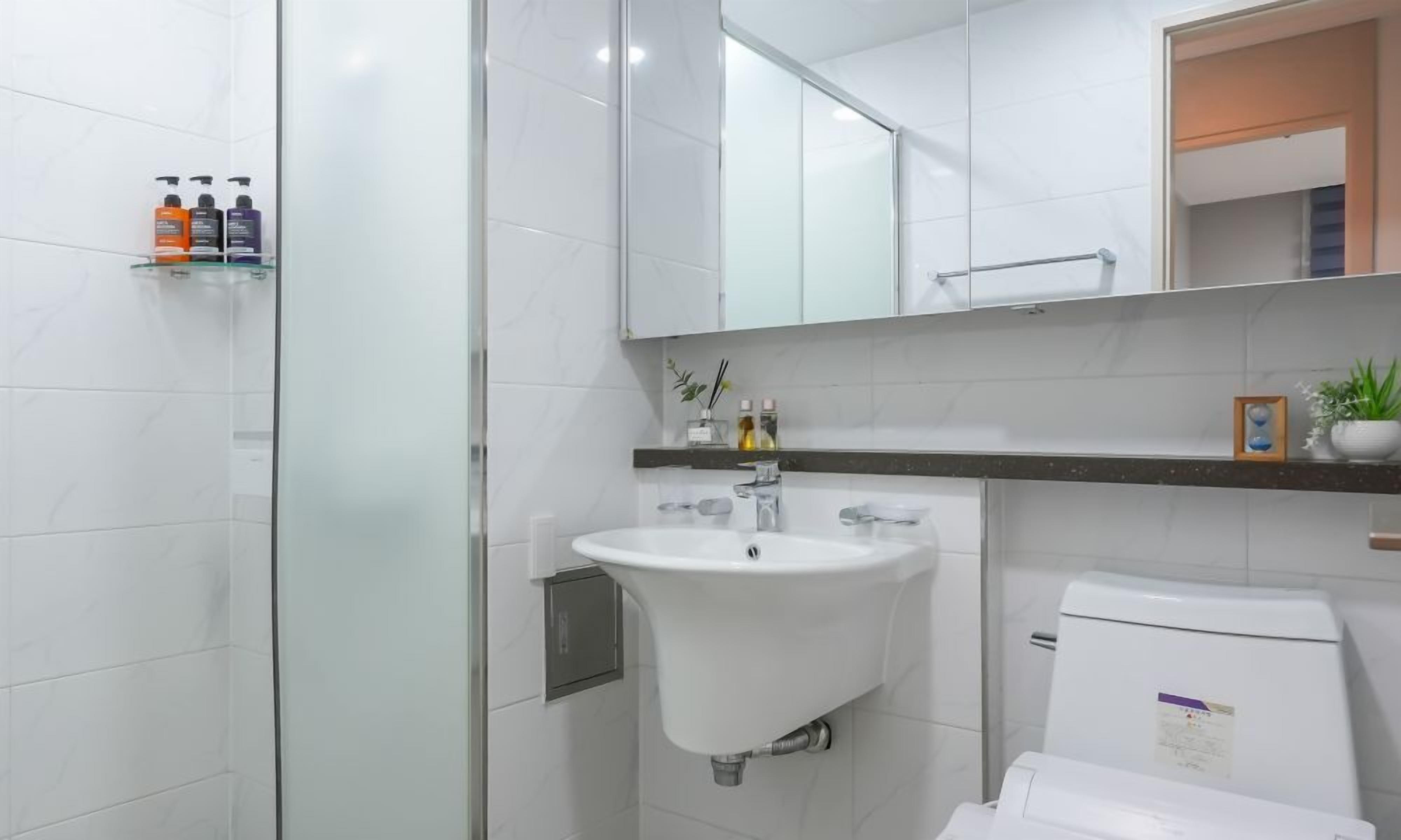 A modern bathroom with a glass shower enclosure, a white sink, and a toilet.
