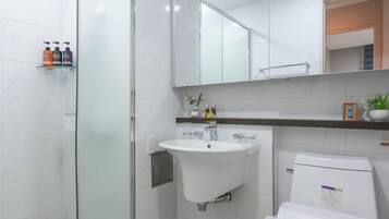 A modern bathroom with a glass shower enclosure, a white sink, and a toilet.
