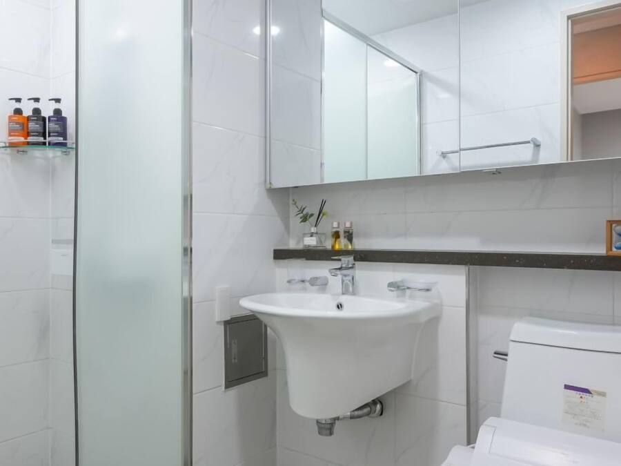 A modern bathroom with a glass shower enclosure, a white sink, and a toilet.