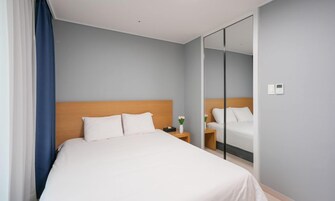 A hotel room with a bed, a nightstand, a mirror, and a thermostat.