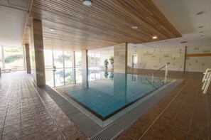 An indoor swimming pool with a wooden ceiling, large windows, and a tiled floor. - FP308 - Apartment close to the beach with a view over the fields - Apartment house (Cuxhaven)