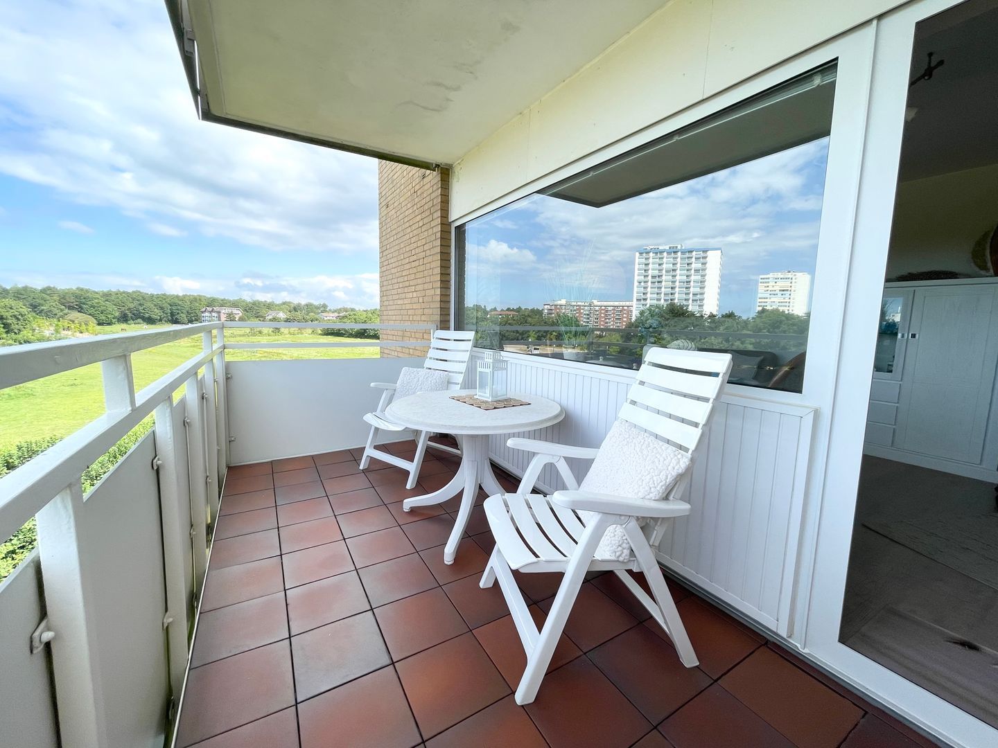 Ein Balkon mit Tisch und Stühlen, Blick auf eine grüne Landschaft und eine Stadt im Hintergrund.