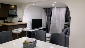 A modern living space with a kitchen, dining area, and a seating area with a TV. - Luxurious Stay  (Bello)