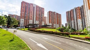 A residential area with high-rise apartment buildings, a road with directional arrows, and green landscaping. - Luxurious Stay  (Bello)