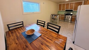 A dining area with a wooden table, chairs, a bowl, and a window. - In Town 2BR: Dedicated Workspace, Free Wifi, Full Kitchen, and Laundry Access. (Fairbanks)
