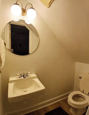 Un baño con lavamanos blanco, inodoro y espejo con iluminación.