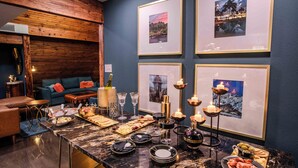 A dining area with a marble table set for a meal, framed pictures on the wall, and a cozy seating area with a sofa and chairs.