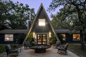Un edificio de forma triangular con un patio central, mesas al aire libre y un hogar para fuego.