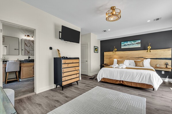 A modern bedroom with a wooden headboard, a large bed, a flat-screen TV, and a wooden dresser. - Professionally Managed | Walk to Beach (Seaside Heights)