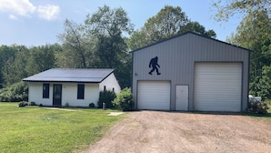 Ein zweistöckiges Gebäude mit Garage, einem kleinen Haus und einem gepflegten Rasen.