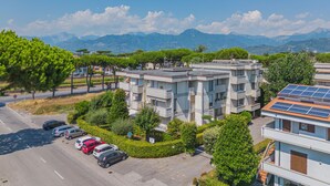 Ein mehrgeschossiges Wohnhaus mit Parkplatz und einer Straße im Vordergrund.