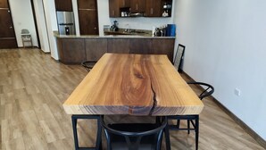 Una mesa de comedor con un diseño único de veta de madera, rodeada de sillas negras en una cocina moderna.