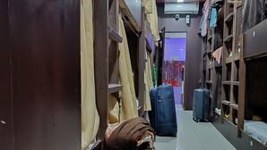 A narrow corridor with luggage and storage shelves. - ASRA DORMITORY  (Mumbai)