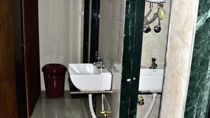 A bathroom with a white sink, a red trash bin, and a marble wall. - ASRA DORMITORY  (Mumbai)