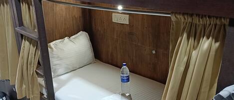 Un lit superposé avec un matelas, une bouteille d’eau et une serviette sur le lit.