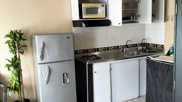 Een koelkast, een microgolfoven, kookgerei, borden en bestek