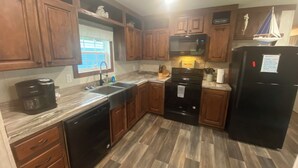 A kitchen with wooden cabinets, a black refrigerator, a microwave, a dishwasher, and a coffee maker. - 9-Guest+River Access+Dogs+powerisOn! (Dunnellon)