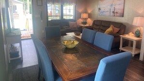 A spacious living room with a wooden dining table, blue upholstered chairs, a brown sofa, and a ceiling fan. - 9-Guest+River Access+Dogs+powerisOn! (Dunnellon)