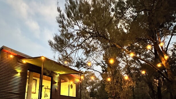 A rustic cabin with a porch, surrounded by trees and a grassy yard. - Romantic tiny house escape amongst wineries & MTB Trails. Fire Pit, Creekside (Lidster)