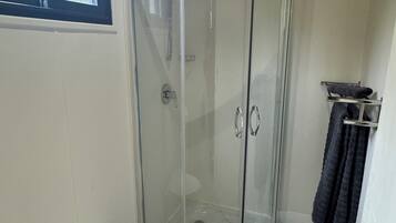 A bathroom with a glass-enclosed shower, a white toilet, and a towel rack.