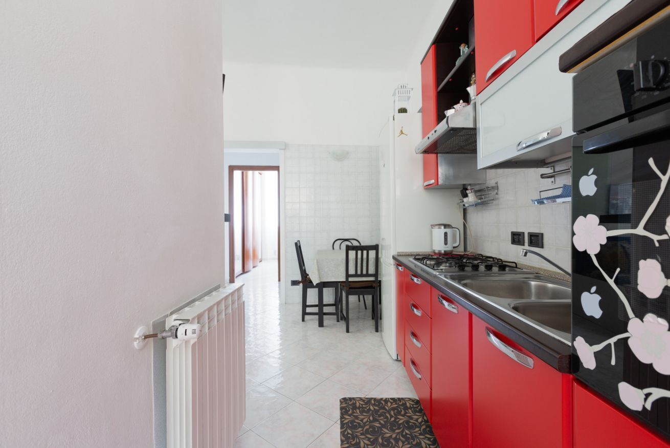 A kitchen with red cabinets, a gas stove, and a sink.