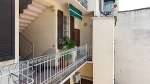 Un immeuble résidentiel doté d’un balcon, d’un escalier et d’une plante en pot.