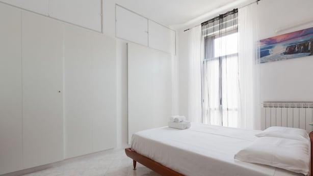 Une chambre à coucher avec un lit, une table en verre, une armoire et un tableau accroché au mur.