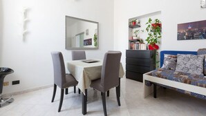 Un coin repas avec une table et des chaises, un canapé, une bibliothèque et un miroir au mur.