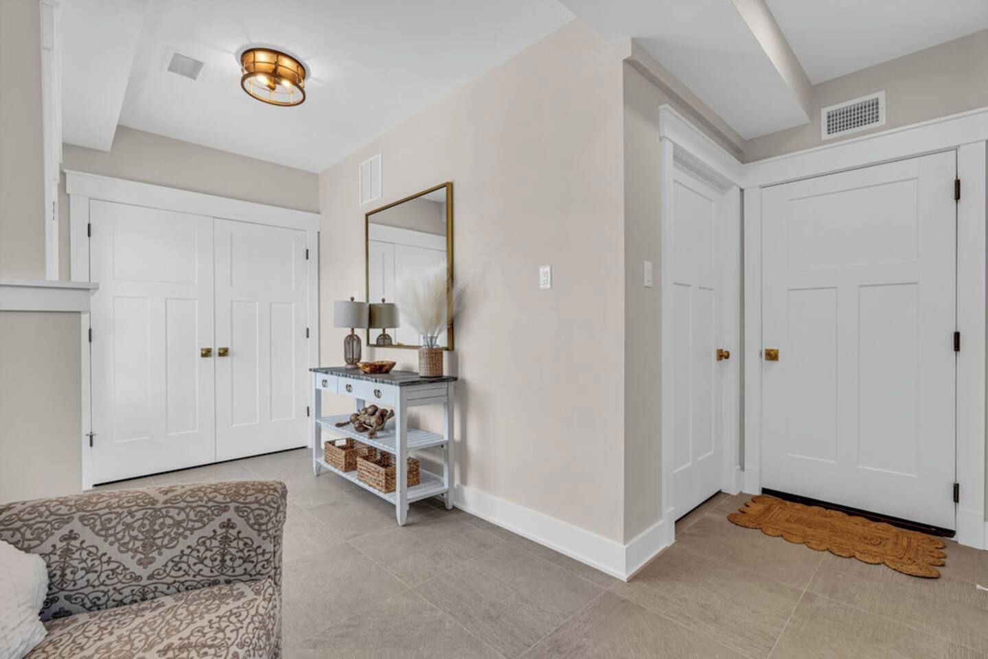 A hallway with white doors, a console table with decorative items, and patterned carpet.