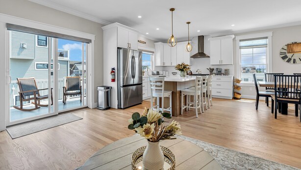 A modern kitchen with white cabinets, stainless steel appliances, and a dining area with a wooden table and chairs. - Professionally Managed | 1 Block to Beach (Seaside Park)