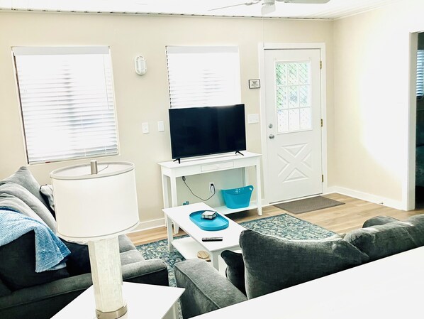 Un salon avec un canapé, un téléviseur, une lampe et une petite table sur laquelle se trouve un plateau bleu.