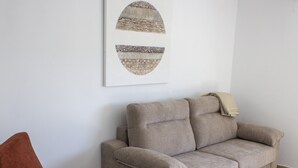 Uma sala de estar com um sofá bege, uma poltrona vermelha e uma mesa de centro branca.