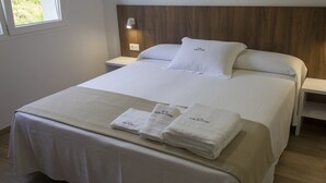 A neatly made bed with white linens, a headboard, and two bedside tables with lamps.