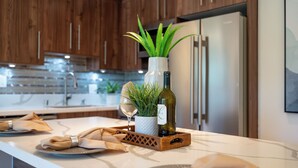 Une cuisine moderne avec des meubles en bois, un plan de travail en marbre et une cave à vin intégrée.