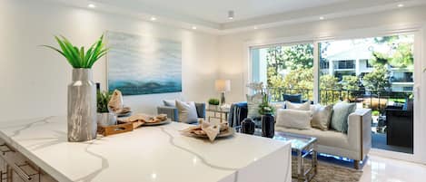 A modern living room with a marble island, a large painting, and a view of the outdoors.